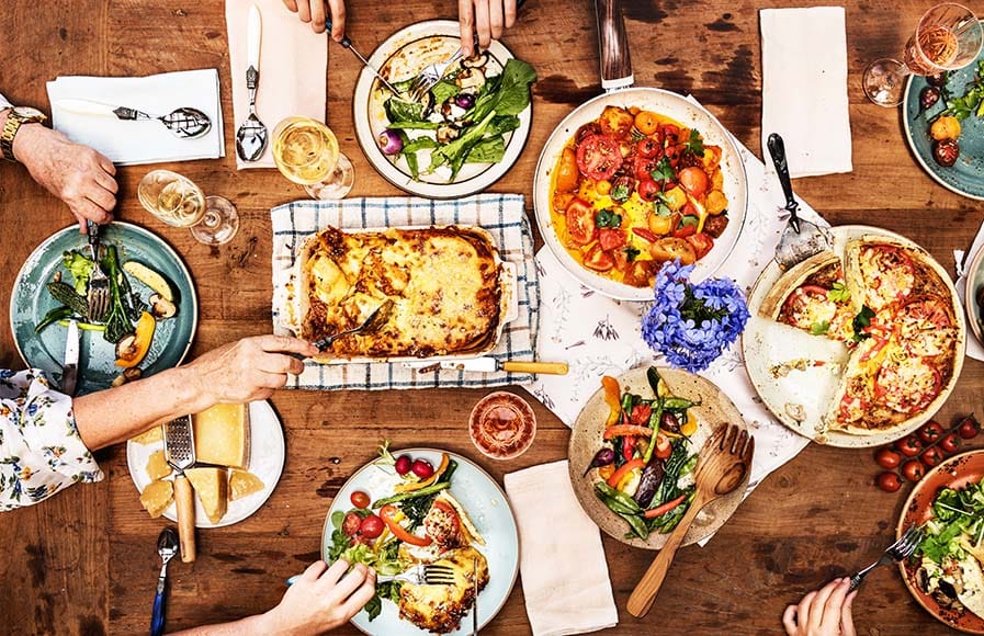 Mesa com pizza, massas e vegetais